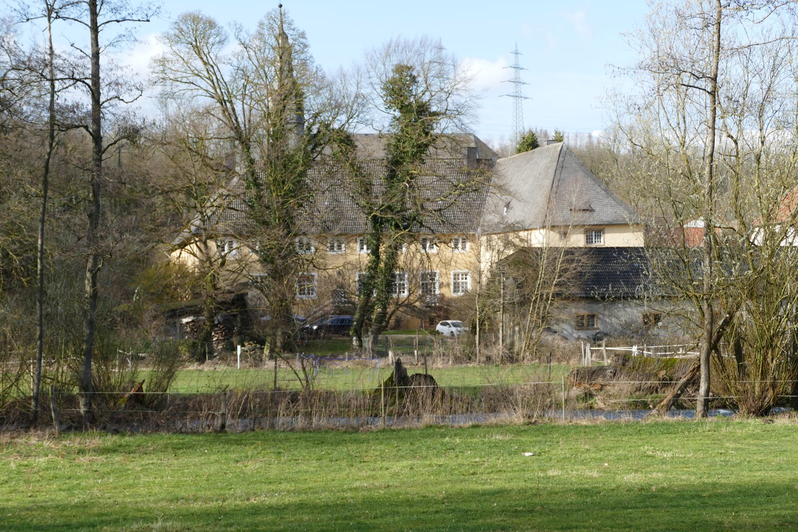 Noch kann man das Wohngebäude durch Büsche und Bäume erkennen