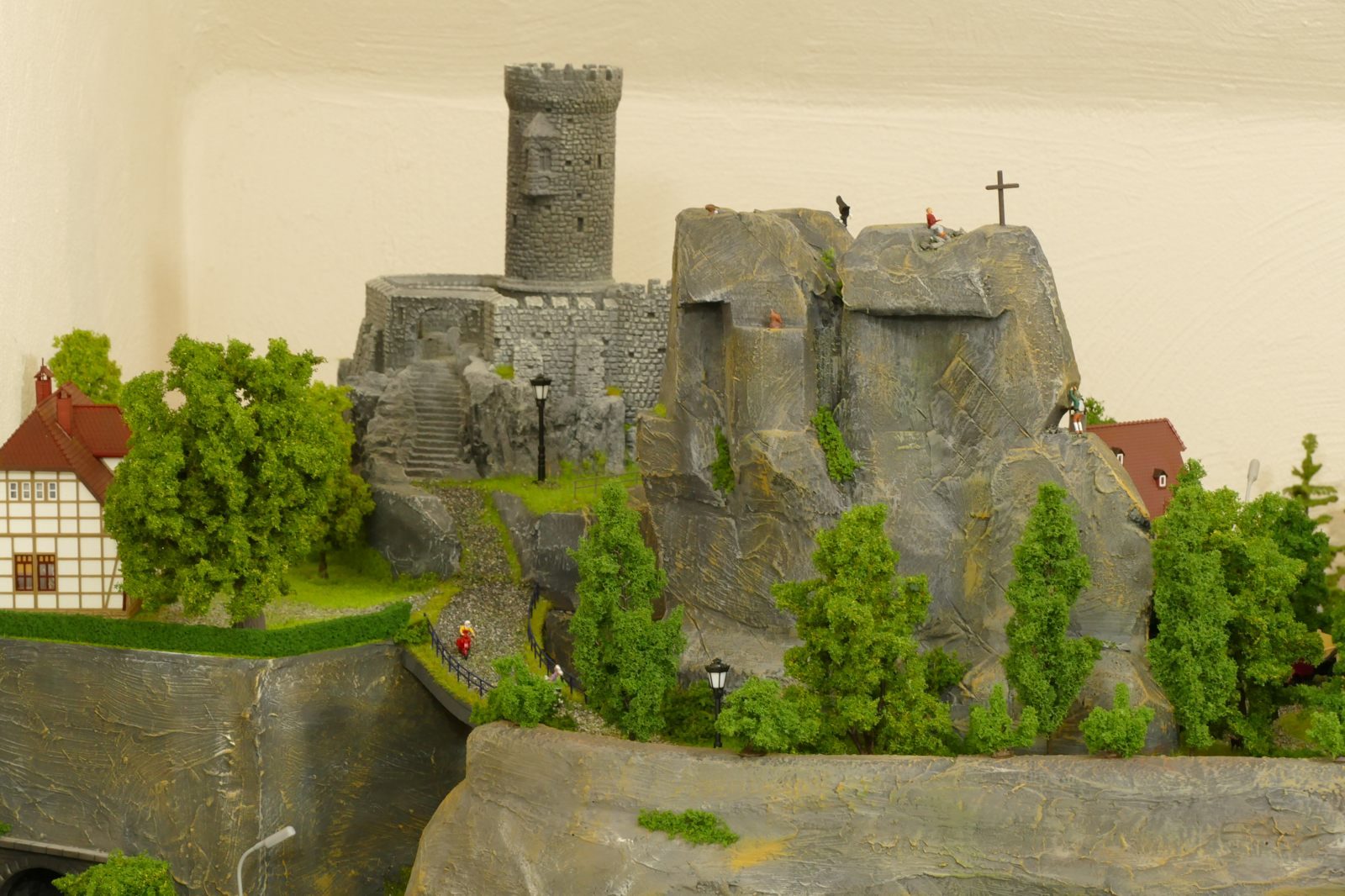 Der Waldweg verläuft unter Bäumen und mündet an der Ruine und dem Haus