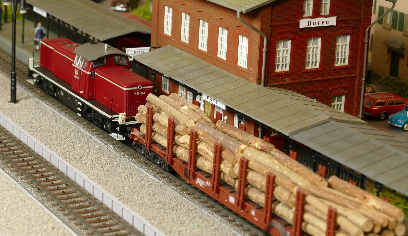 Eine V90 zieht einen langen Holzzug durch den Bürener Bahnhof